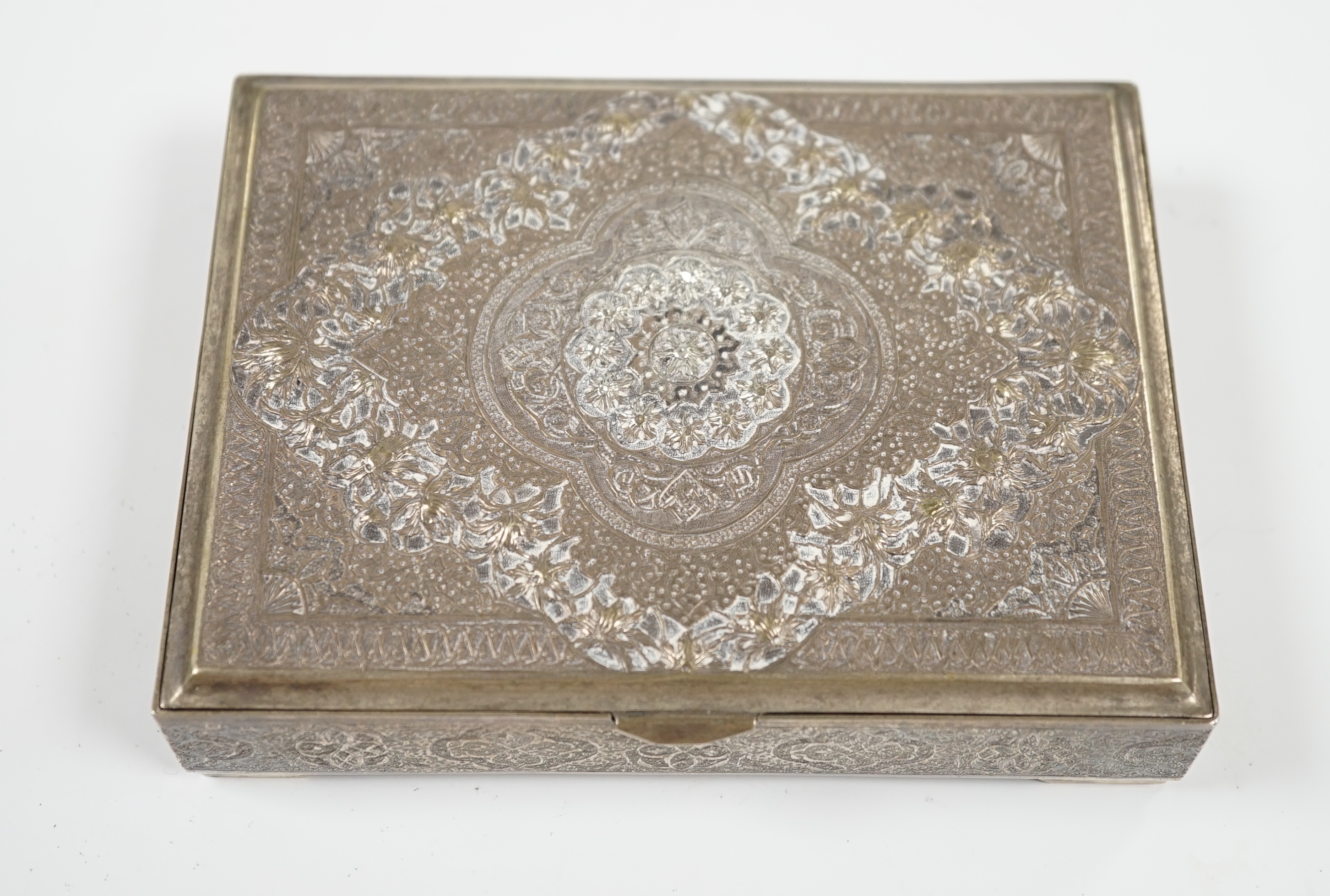 A Persian embossed white metal rectangular cigarette box, on small bracket feet, 12.2cm, 8.6oz. Condition - fair